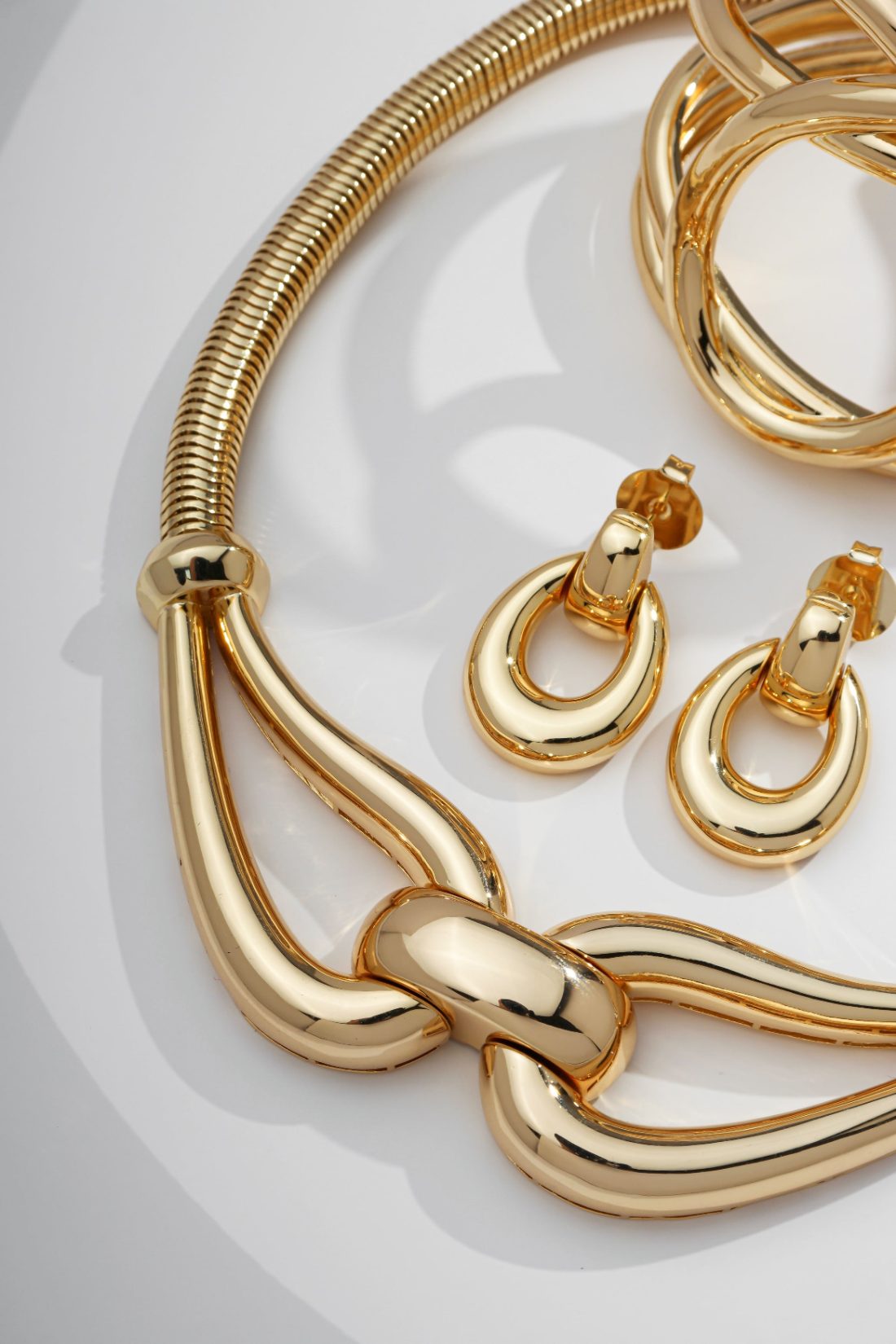 Colar, pulseira e brincos dourados Lolita Joias sobre fundo claro